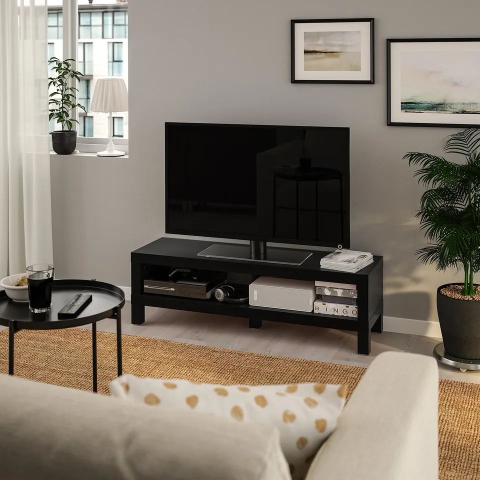 BLACK LACK tv stand fits tv perfectly, smaller than couch, holds books & plants, dark wood floor & light walls.