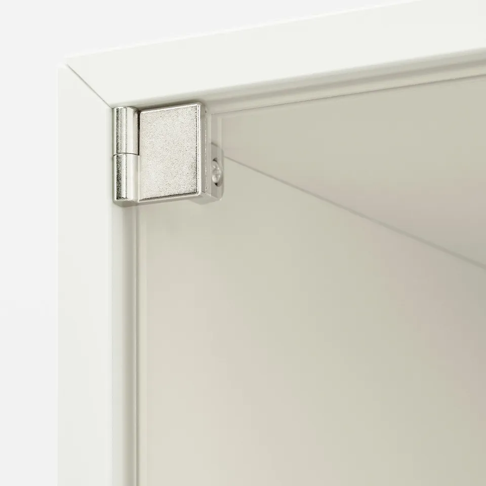 A close-up of a high-quality, white cabinet corner with a silver hinge, indicating robust and sleek design.