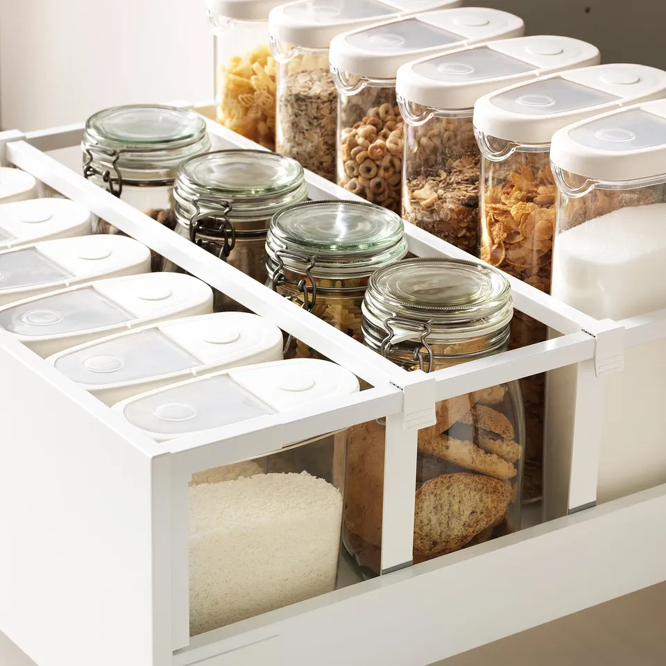 Kitchen drawers with adjustable shelves, storing food in clear jars and containers, showcasing organised space.