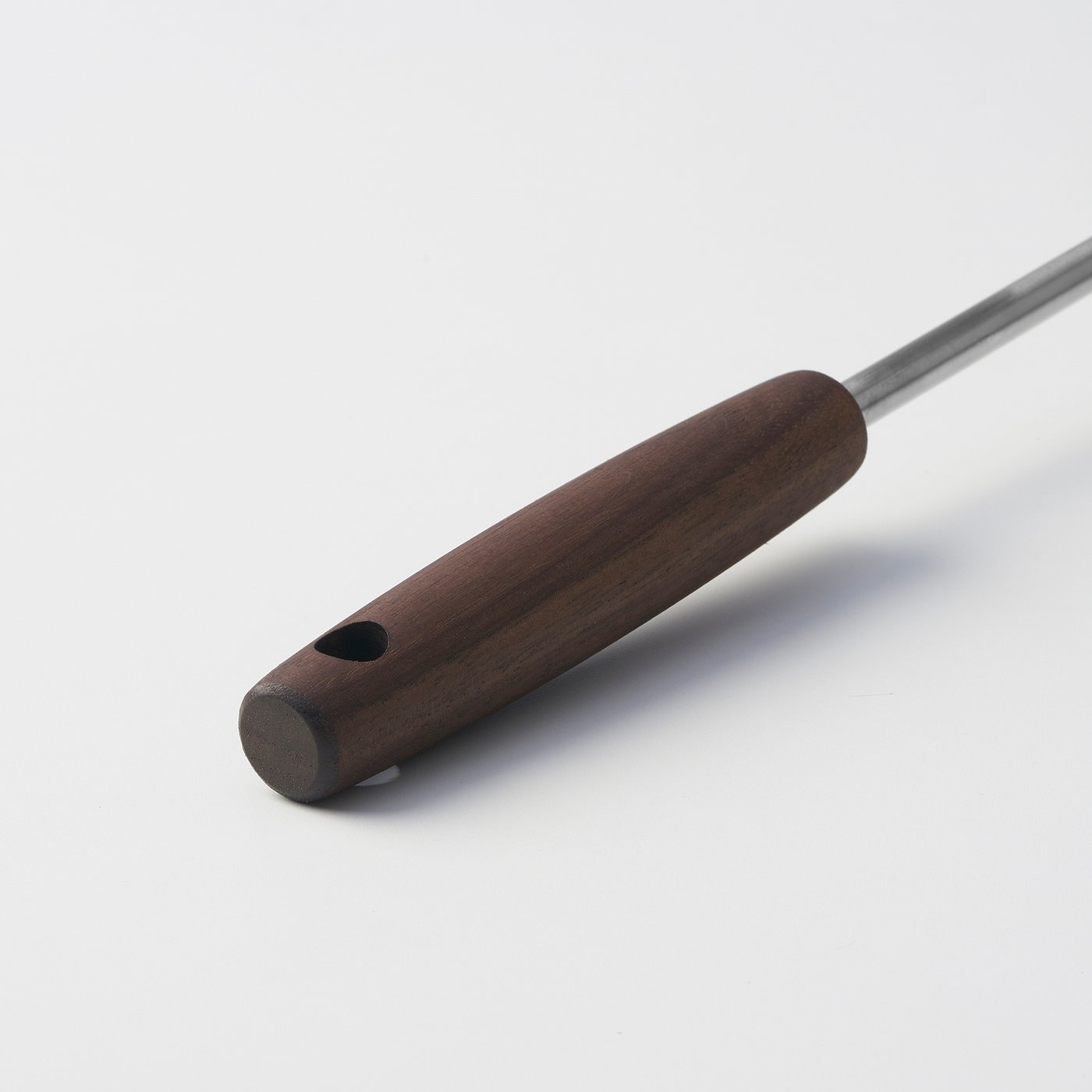 Elegant kitchen tool with dark walnut handle and stainless steel rod, designed for a firm grip and easy storage.