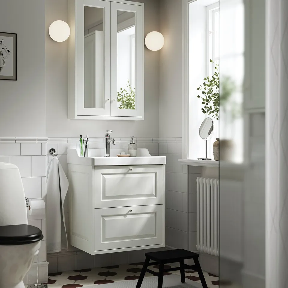 White TÄNNFORSEN vanity, 2 drawers, ceramic sink, mirrored cabinet with lights, black stool, window, radiator.