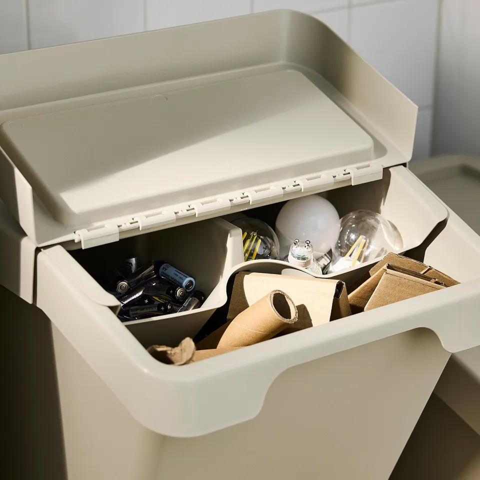 Open beige SORTERA storage box showing batteries and light bulbs inside, ideal for organising small items.