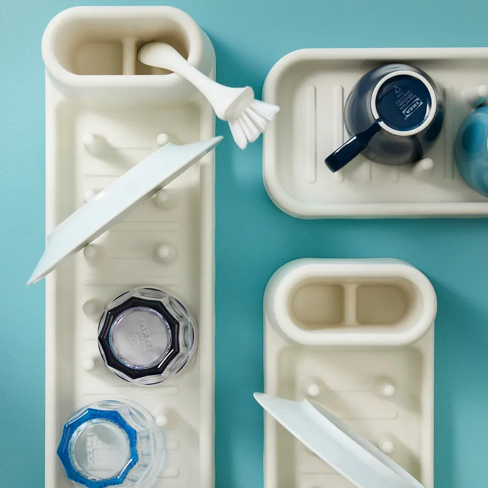 White dish trays with blue containers, knives, and brushes for cleaning and organising dishes.