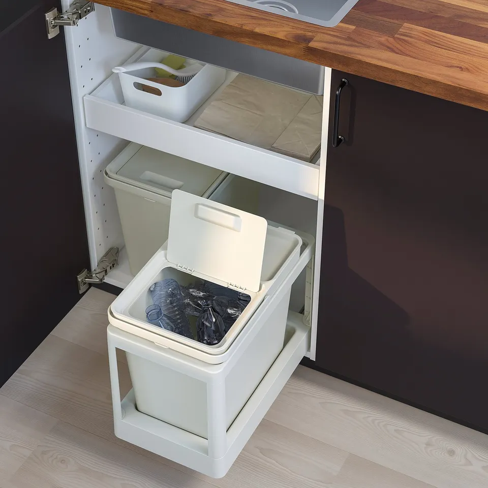 A white HÅLLBAR waste sorting bin inside a pull-out cabinet frame under a kitchen sink, designed for efficient recycling.