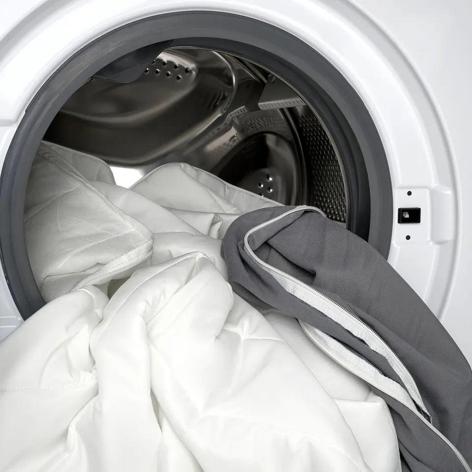 Mattress pad in washing machine, removable cover for easy cleaning.