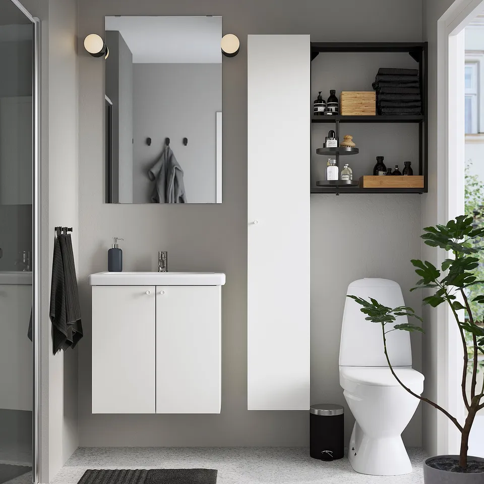 Modern bathroom with ENHET storage, sink cabinet, mirror, toilet, & high cabinet. Dark accents.