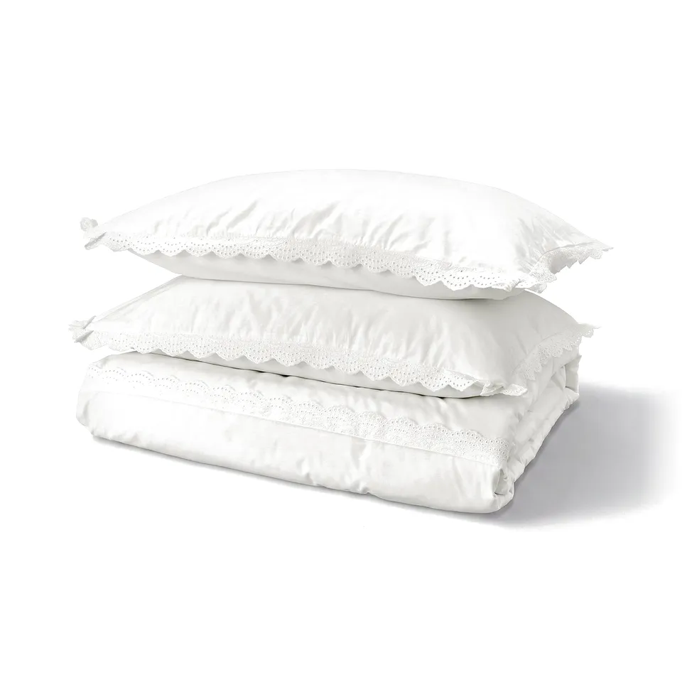 Stacked white lace-trimmed cotton bedding: duvet cover & pillowcases.