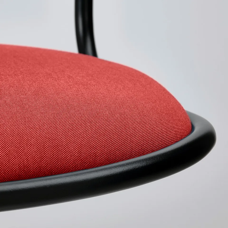 Close-up of a modern chairs red cushion and black frame.