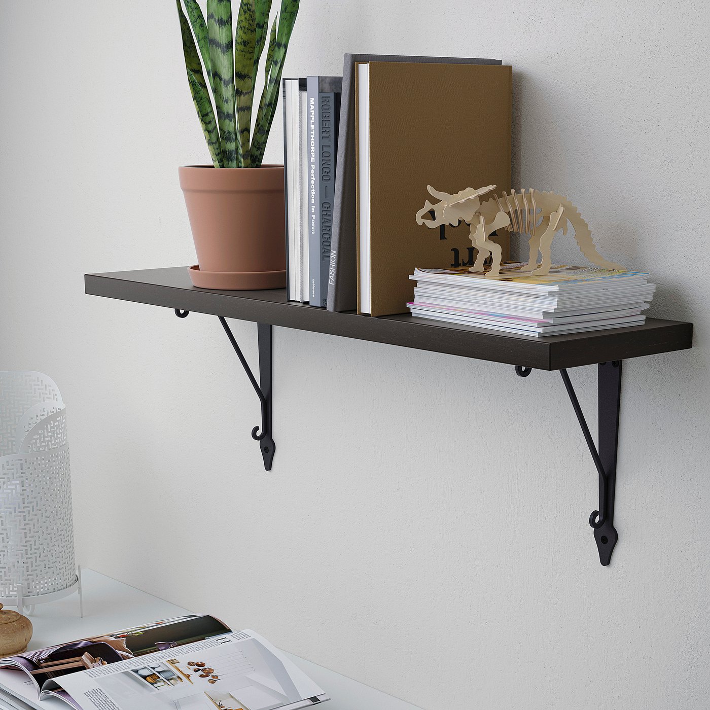 Black wall shelf with books, plant, decor, metal brackets.