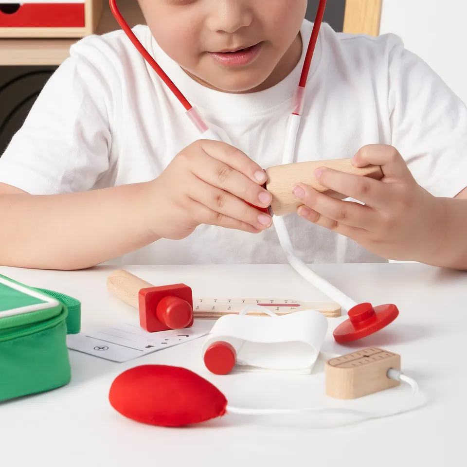 Child plays with doctor toy set, using stethoscope and medical tools, encouraging imaginative play.