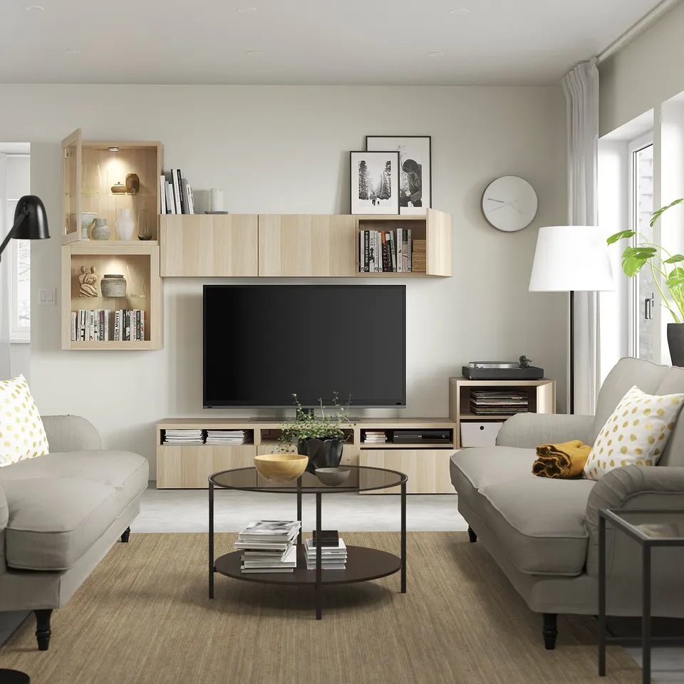 Modern living room with light furniture, tv, books, decor, sofas, and lamp.