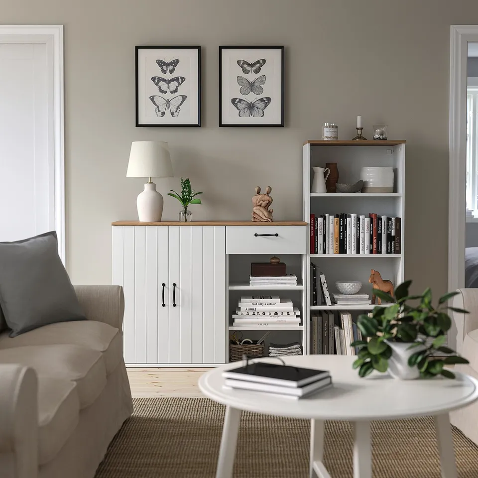 Modern living room with SKRUVBY white sideboard & bookcase, butterfly prints, lamp, plants, and books.