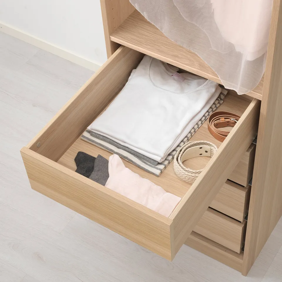 Light wood dresser drawer with folded clothes and belts, part of the KOMPLEMENT system for organised storage.