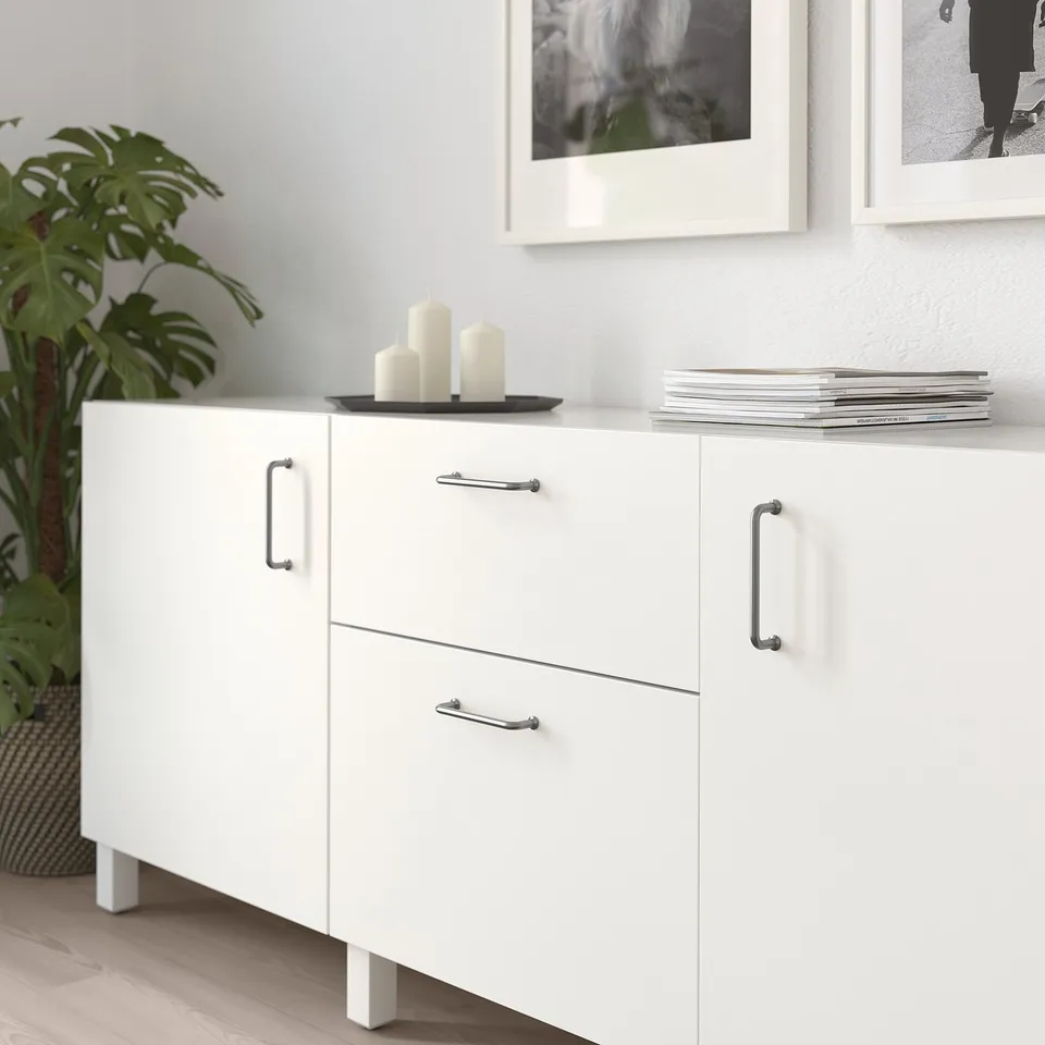 White cabinet with BAGGANÄS handles and knobs. Drawers and a countertop with items including candles and books.