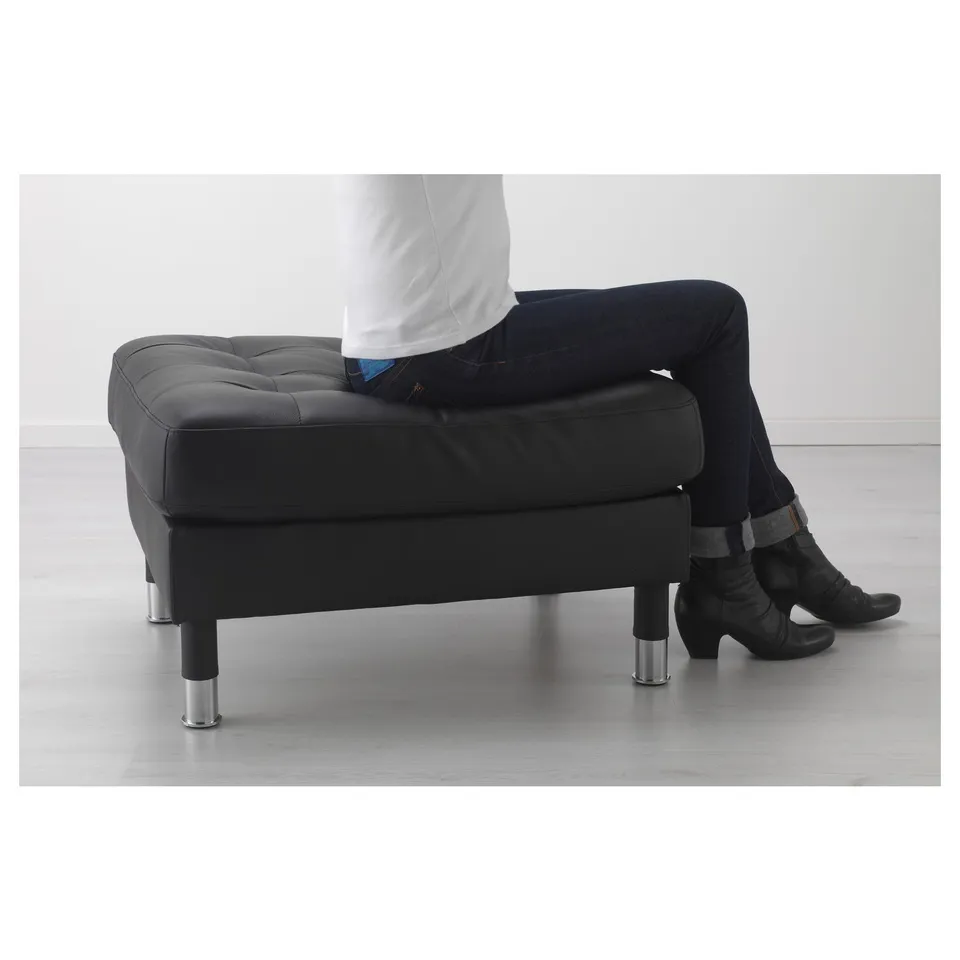 Person sitting on black LANDSKRONA ottoman with chrome legs.