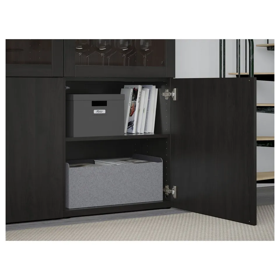 Open black cabinet showing grey storage boxes and books inside.