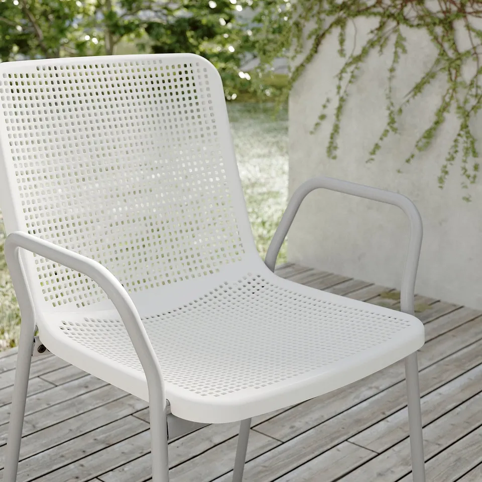 Two white plastic patio chairs on wooden deck near wall.