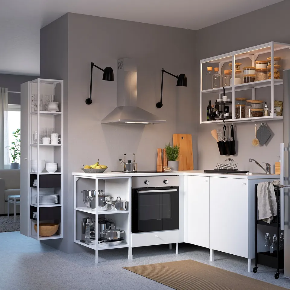 Modern kitchen with white ENHET storage. Cabinets & shelves hold dishes, pots, & utensils. Stainless steel hood & black accents. Spacious & organised.