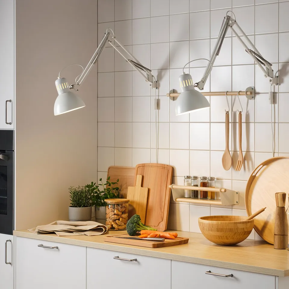 Kitchen counter with veggies lit by TERTIAL lamps. Wooden tools and plant nearby.