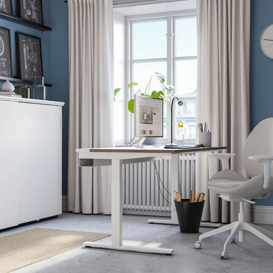 Modern home office with height-adjustable MITTZON desk, natural light, blue walls, and minimal decor.