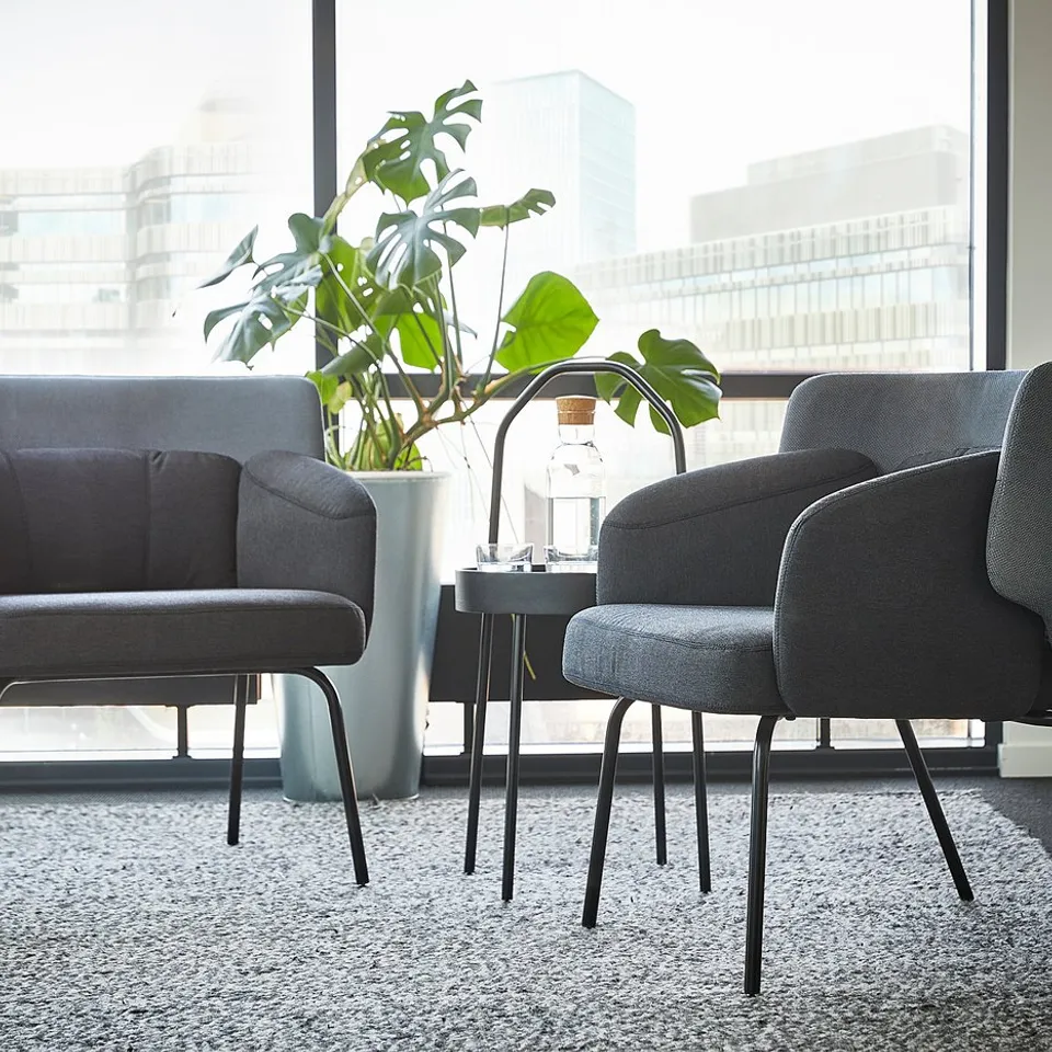Modern office seating area with two grey BINGSTA chairs and a tall plant.