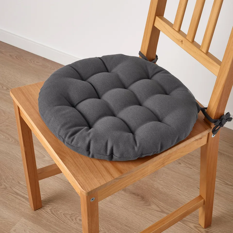 A chair with a dark grey padded seat cushion attached, providing comfort and style. The cushion is secured with fabric ties.