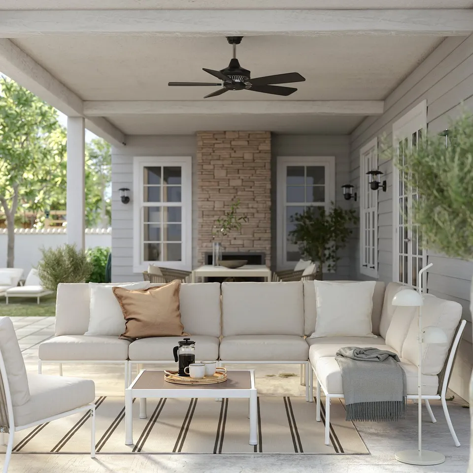 Comfortable outdoor lounge with SEGERÖN white sofa, cushions, coffee table, and potted plants on a patio.