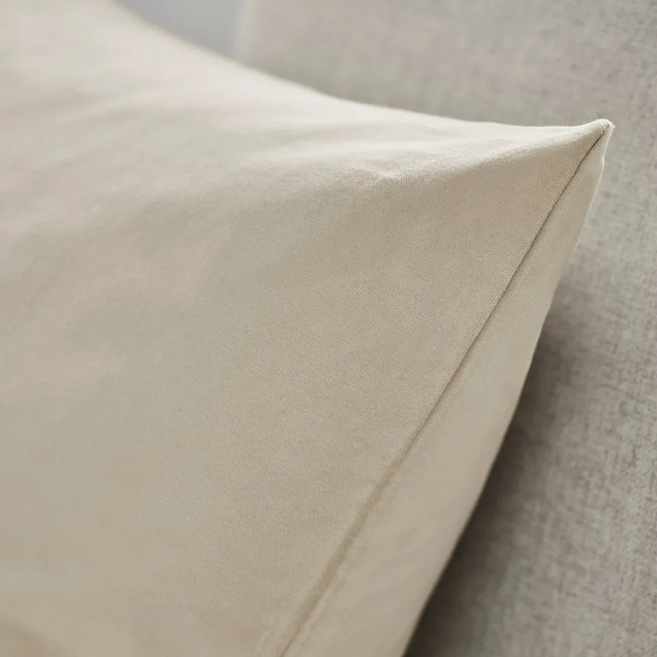 Close-up of plush, beige cotton velvet cushion cover with neat stitching, showcasing soft fabric texture.