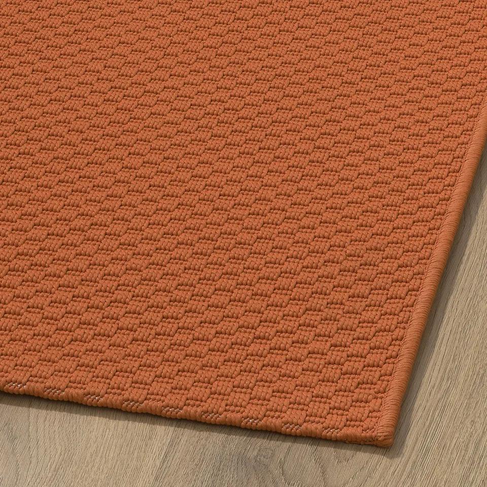 Close-up of a bright orange textured rug, showcasing its tightly woven, durable surface.