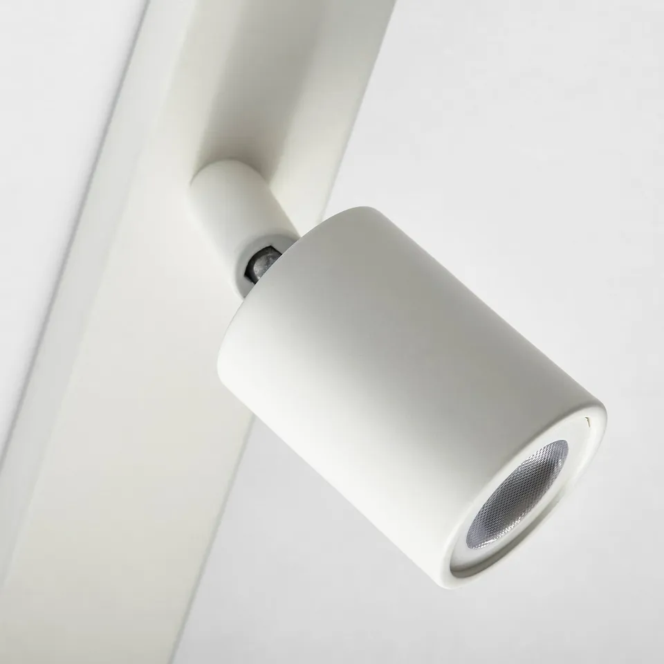 Cylindrical silver track light mounted on white ceiling. Slim, modern design with individually adjustable spotlight.