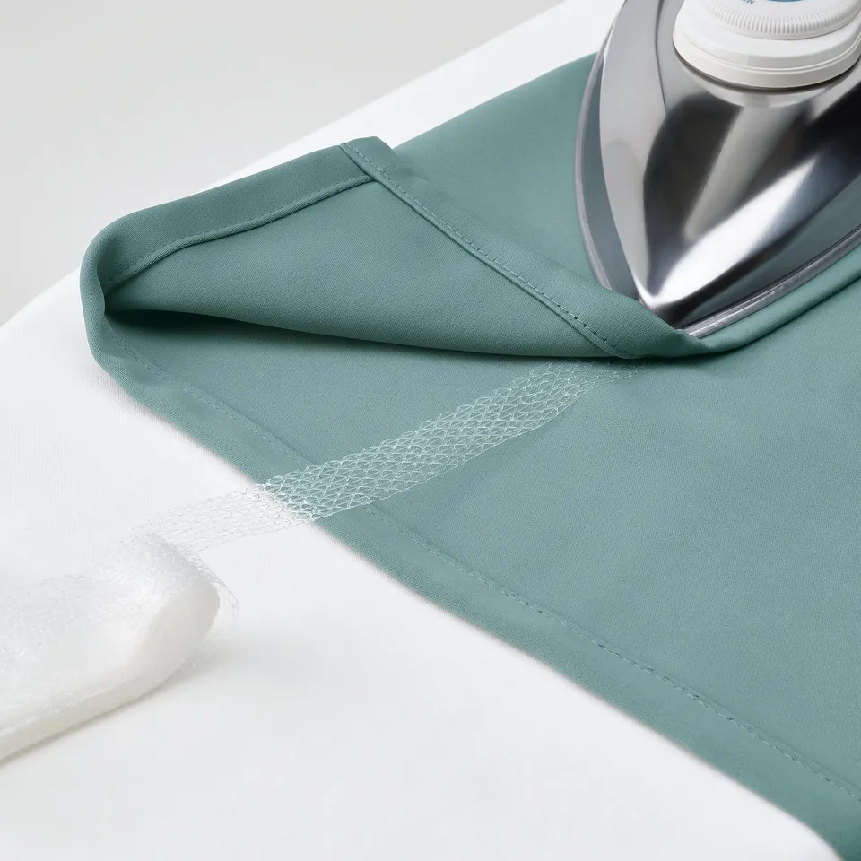 A green fabric piece is being ironed, likely demonstrating its ability to be wrinkle-free and smooth.