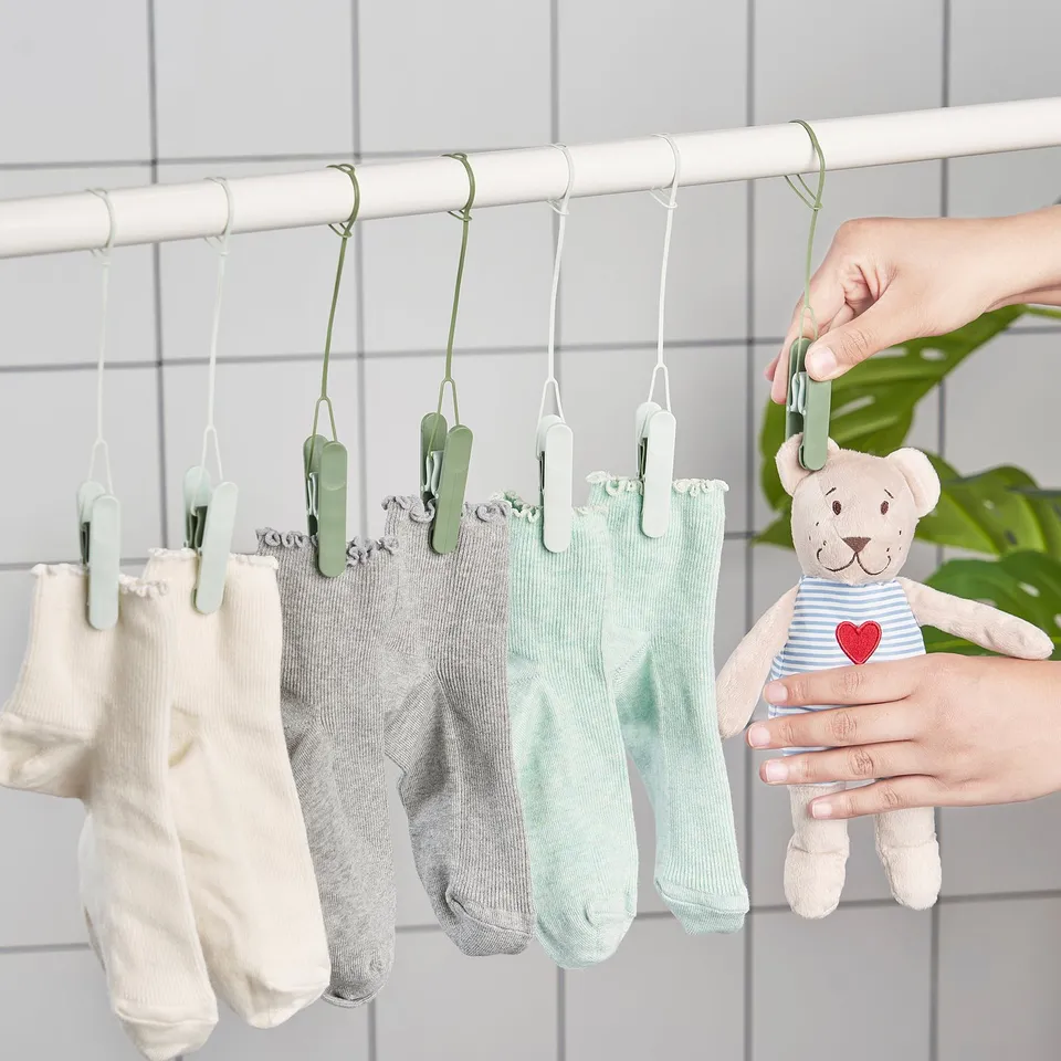 A person hangs socks on drying pegs, showcasing their versatility and ease of use on a towel rail.
