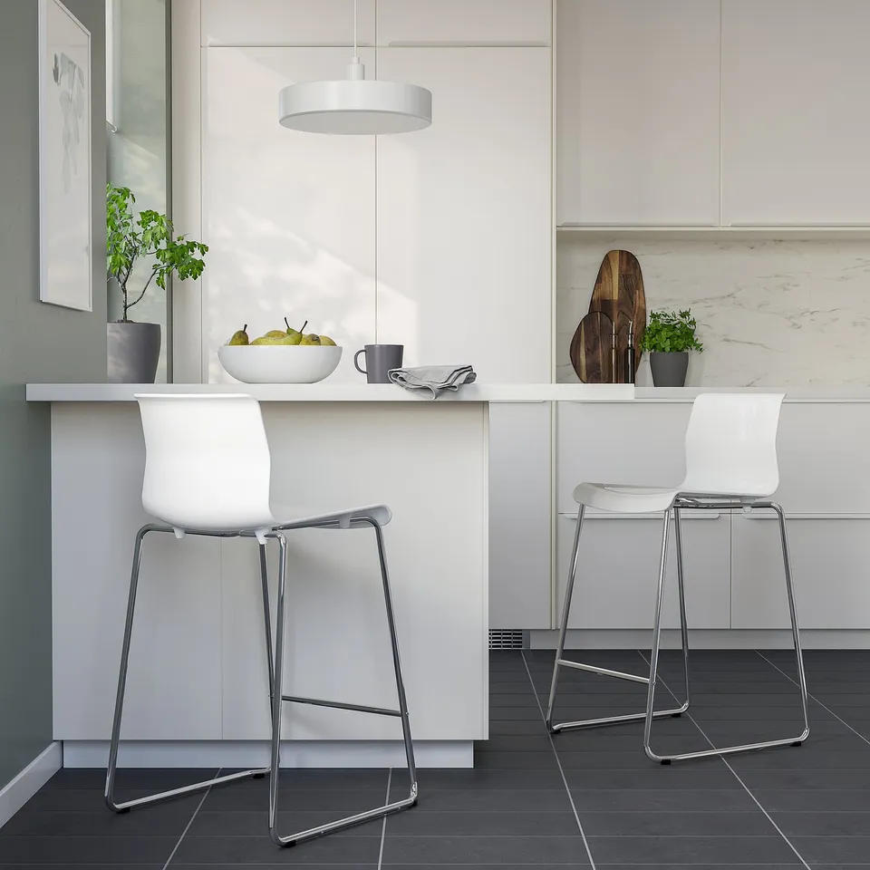 Modern kitchen with stackable GLENN stools, chrome legs, fruit bowl, and grey mug.