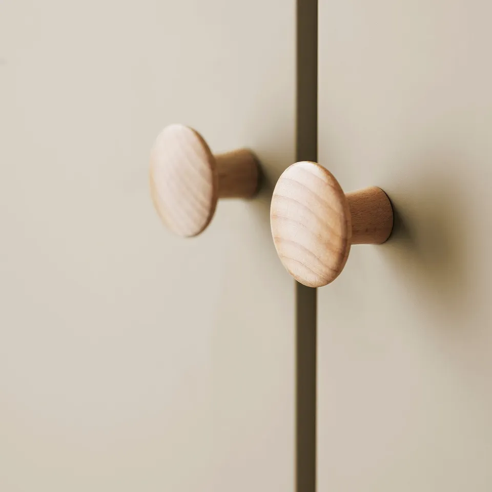 Two wooden knobs mounted on a light-colored cabinet, showcasing their smooth, polished finish and solid craftsmanship.