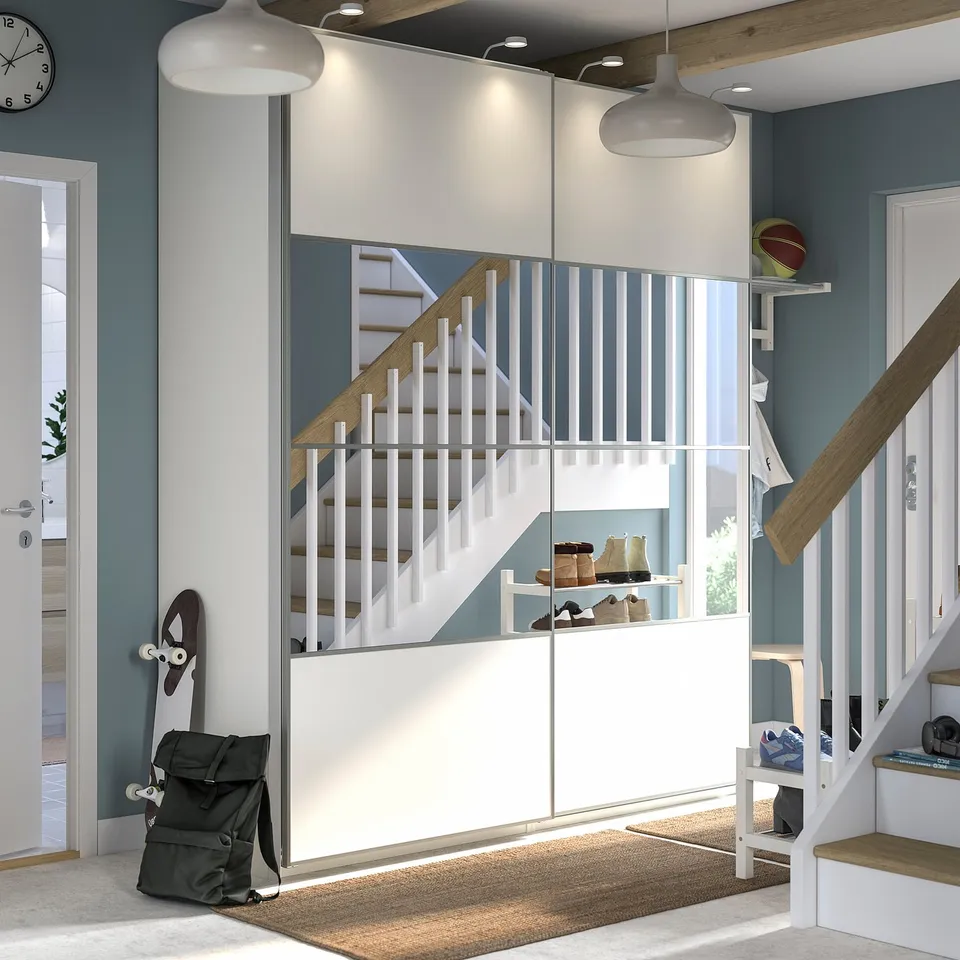 Modern hallway a white PAX storage unit with mirrored doors, wooden steps, and hanging items.