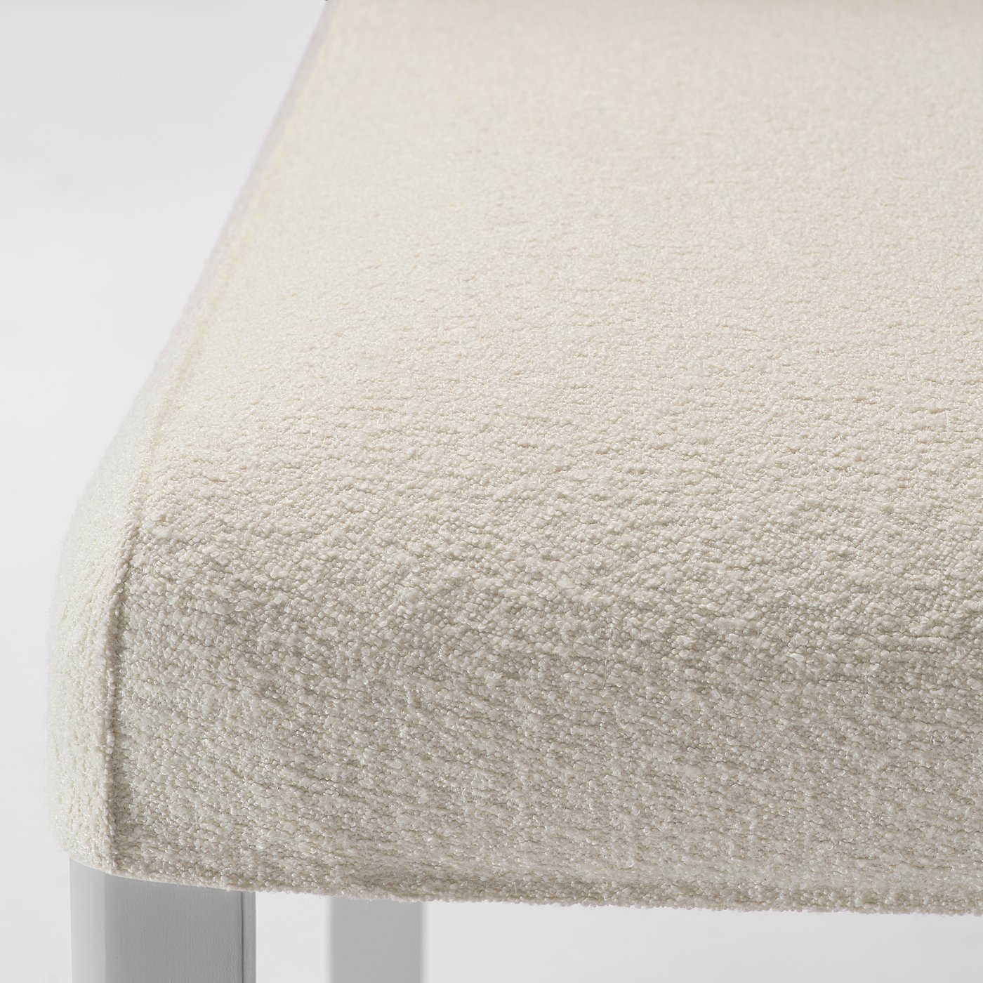 A close-up of a beige upholstered chair with a textured fabric, emphasising its soft and durable quality.