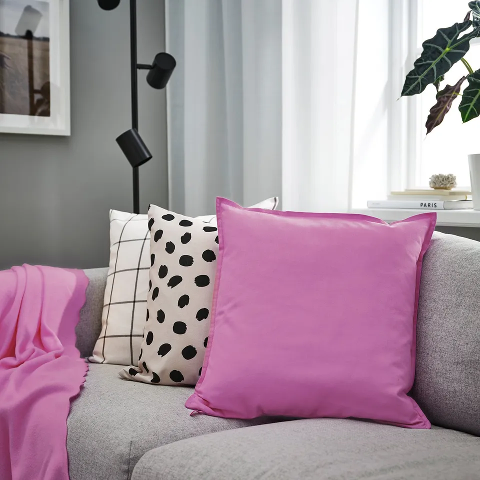 Living room with grey sofa and vibrant magenta GURLI cushion among chequered & polka dot pillows.