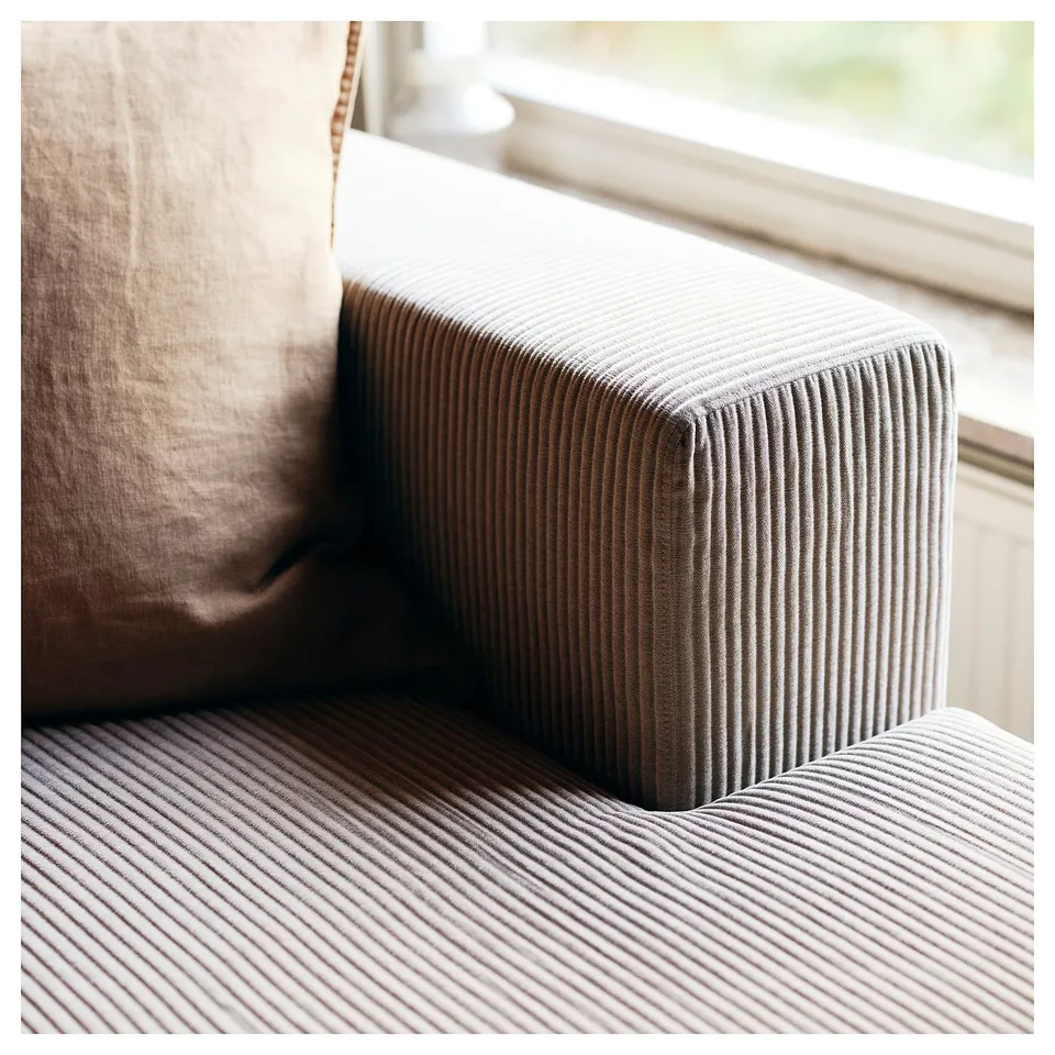 Modern sofa close-up: grey corduroy, cushioned seat, sleek lines.