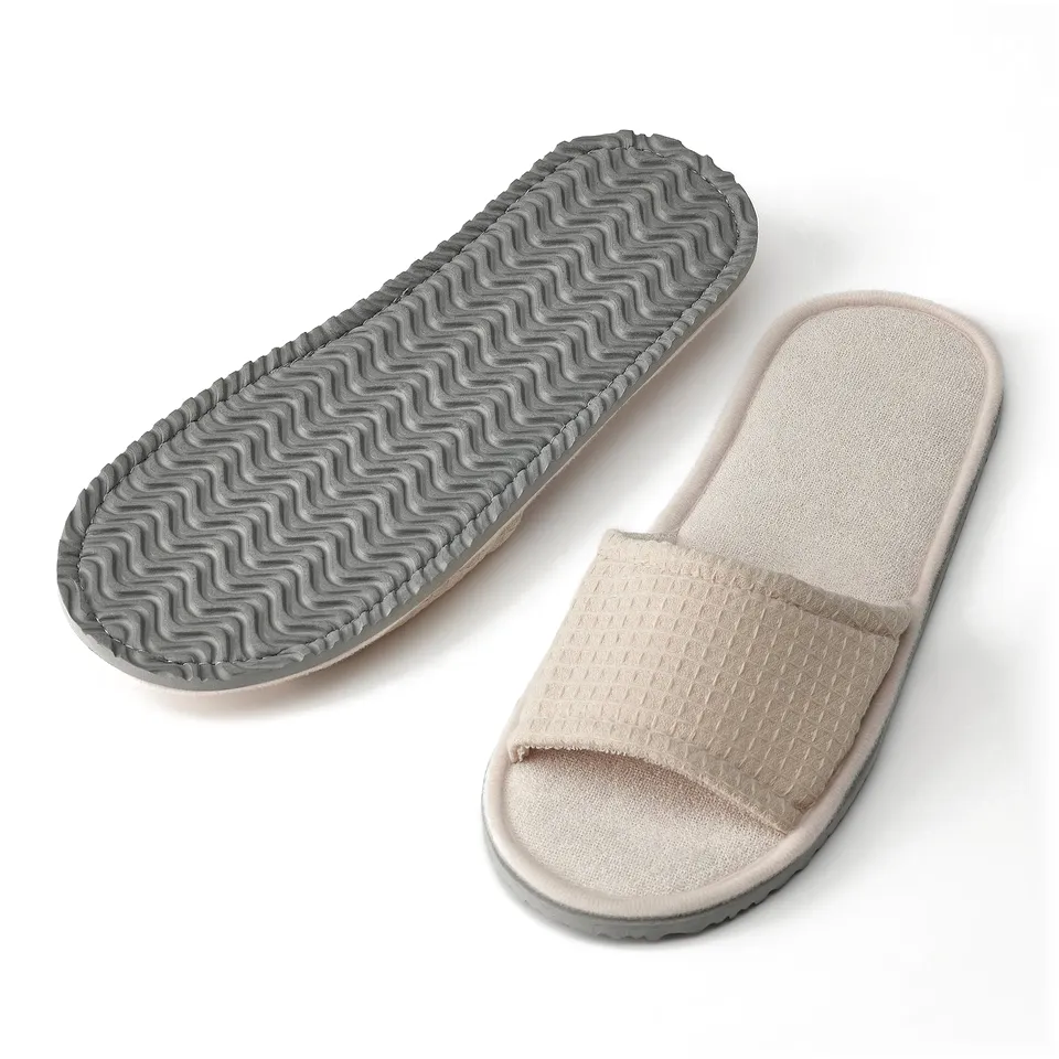 Two waffle-textured, open-toe slippers with cushioned soles, one shown from bottom displaying wagged sole for grip.