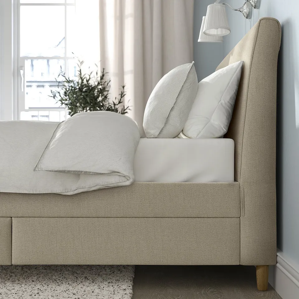 Cosy bed with sloping headboard, soft pillows, and drawers for storage.