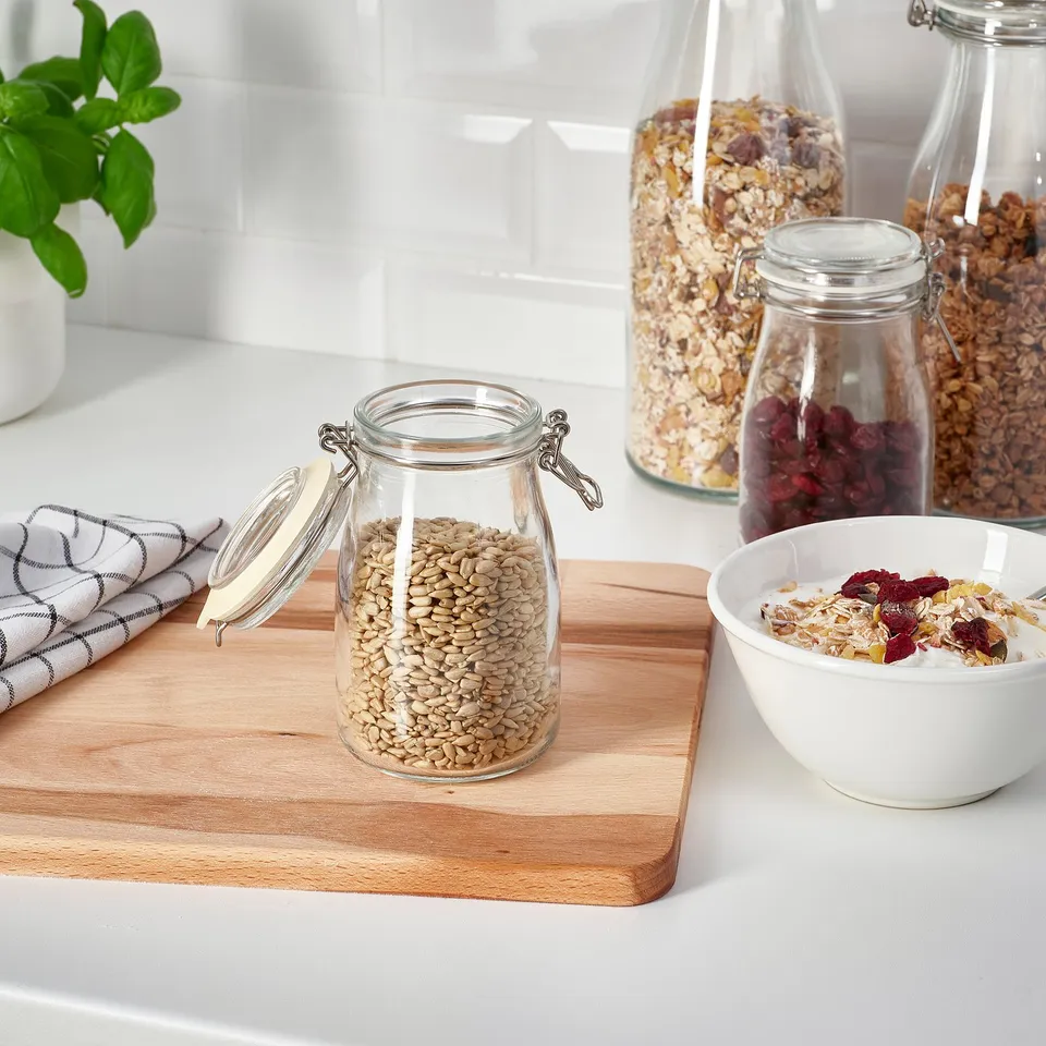 Countertop display with glass jars storing seeds and dried fruits; bowl of mixed cereal beside.