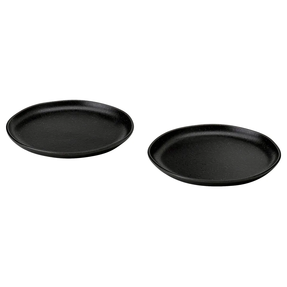 Two black, round, matte stoneware plates with a rustic, textured surface displayed side by side.