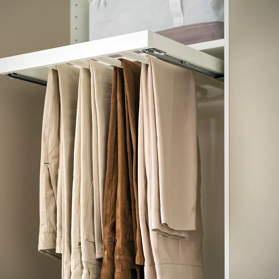 KOMPLEMENT trouser hanger in white, hangs beige and brown trousers neatly in a wardrobe.