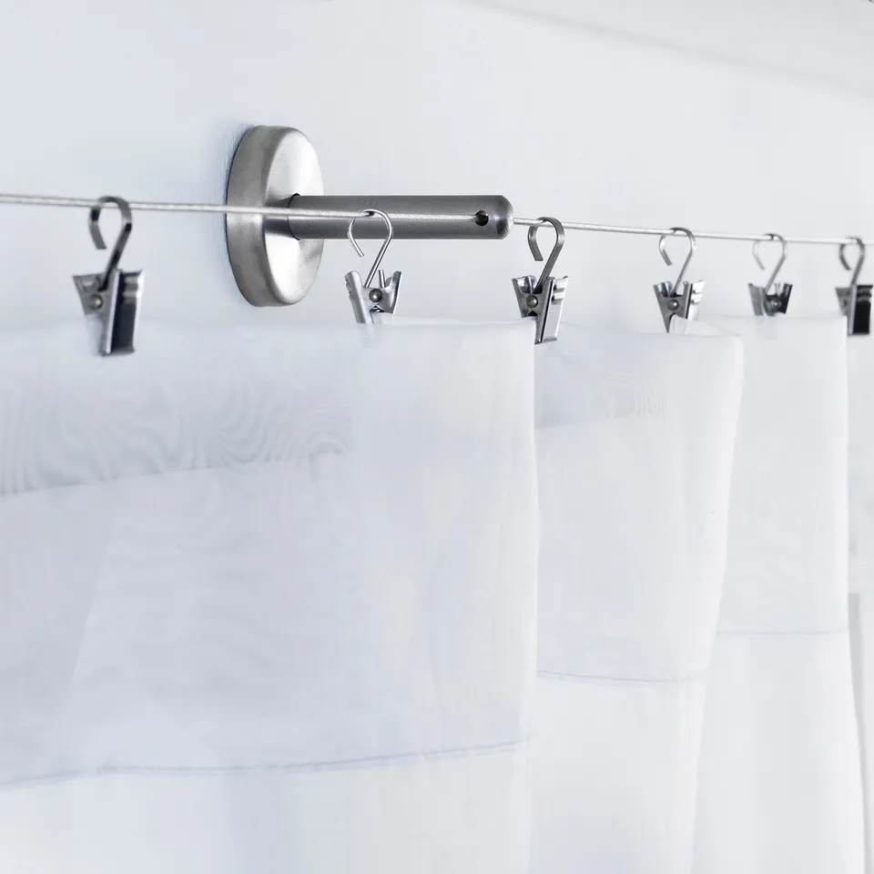 Aesthetic silver curtain rod with hooks, holding white, sheer curtains.
