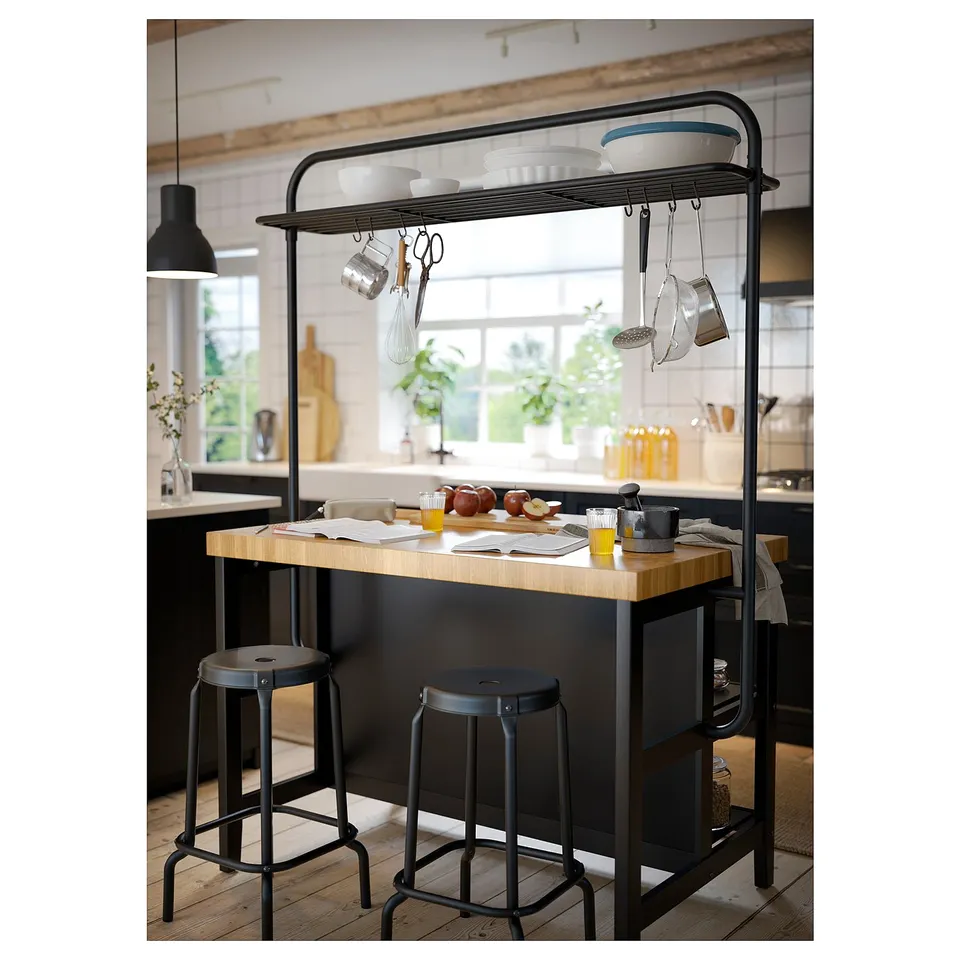 Black kitchen island with wooden top, hanging utensils, and two stools.