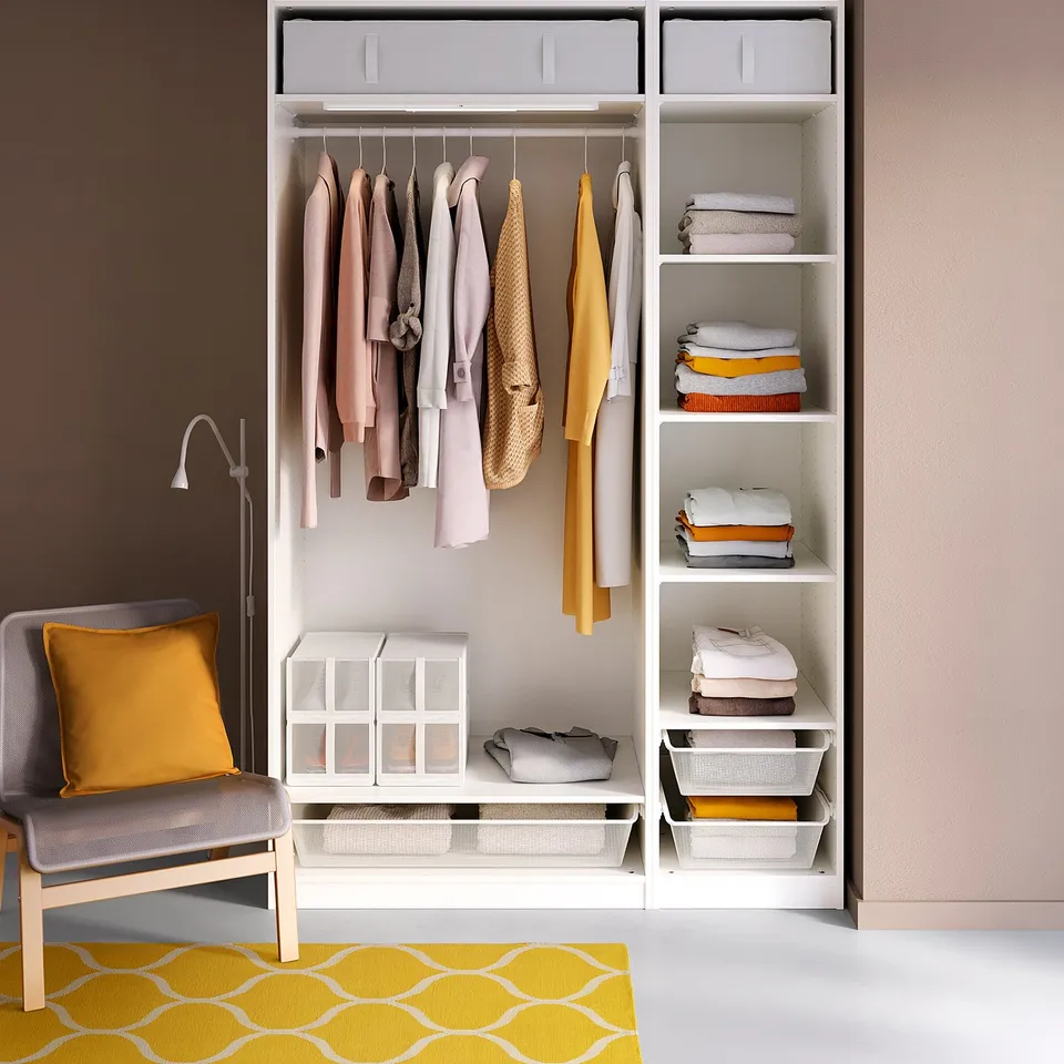 Modern wardrobe with colourful clothing, organised shelves, and a cosy chair.