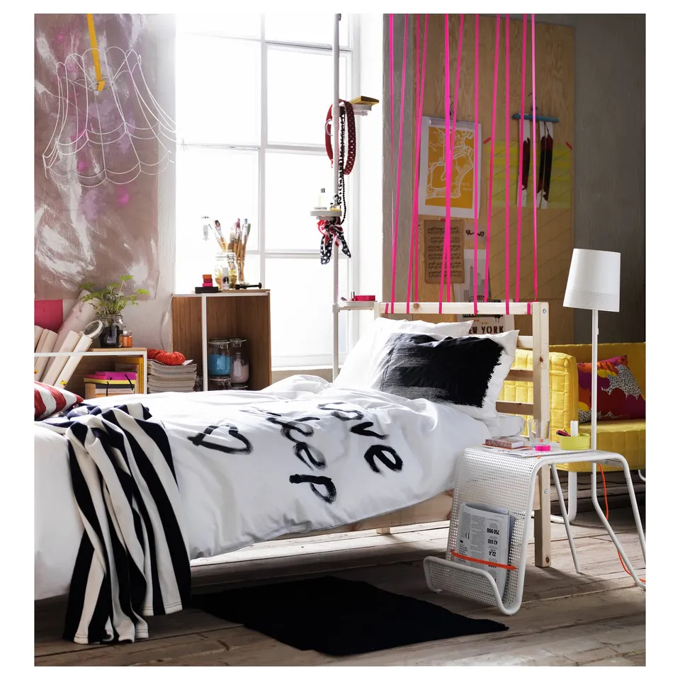 Creative bedroom featuring a white TARVA bed frame with sleep graphic duvet, black and white striped blanket, and colourful decorations.