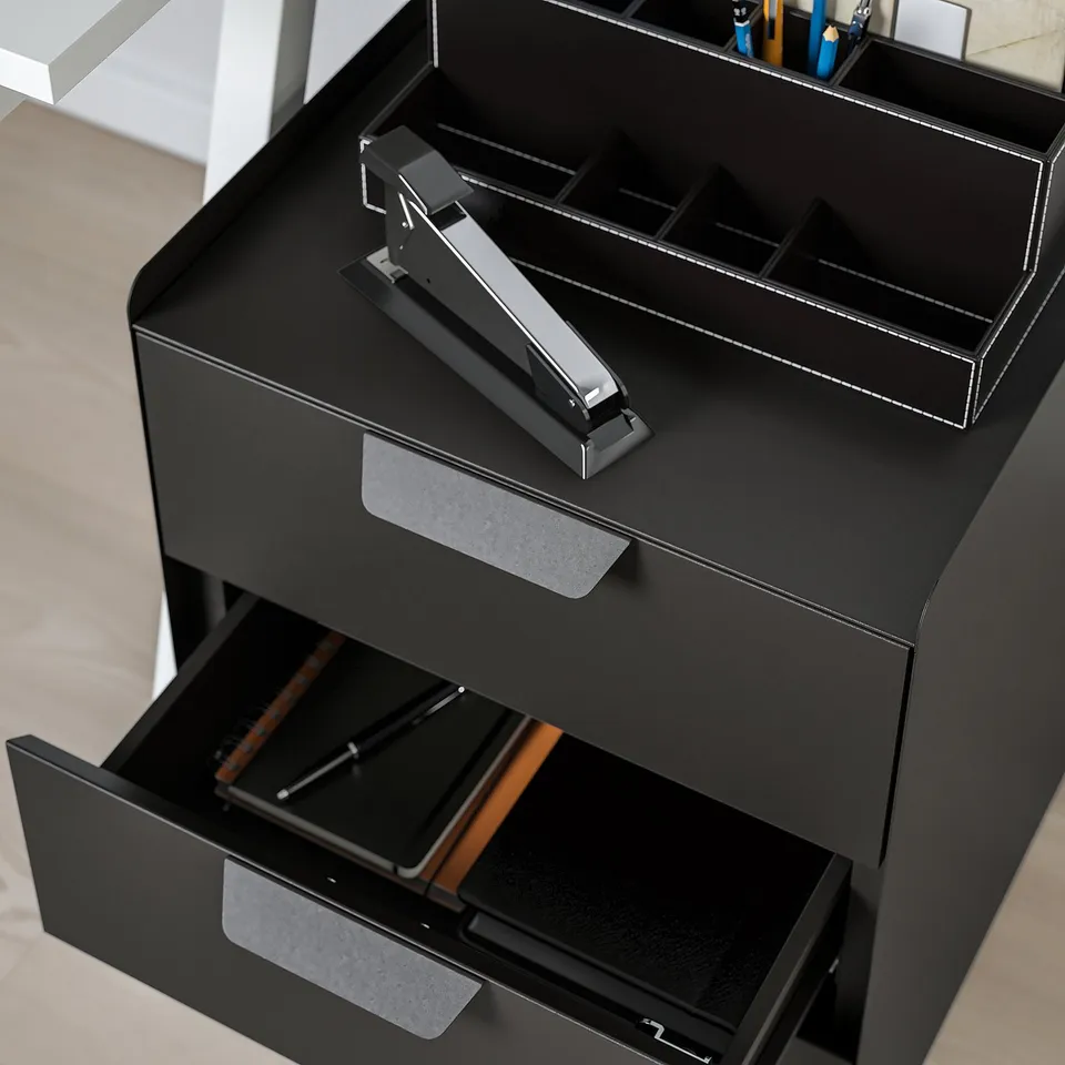 Black desk with open drawer and built-in stapler.