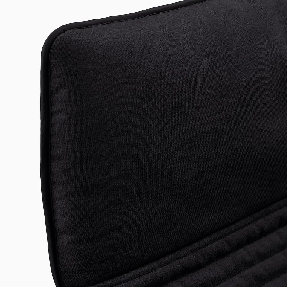 Black cushioned chair, smooth fabric, rectangular shape, neatly stitched edges, appears comfortable and well-crafted.
