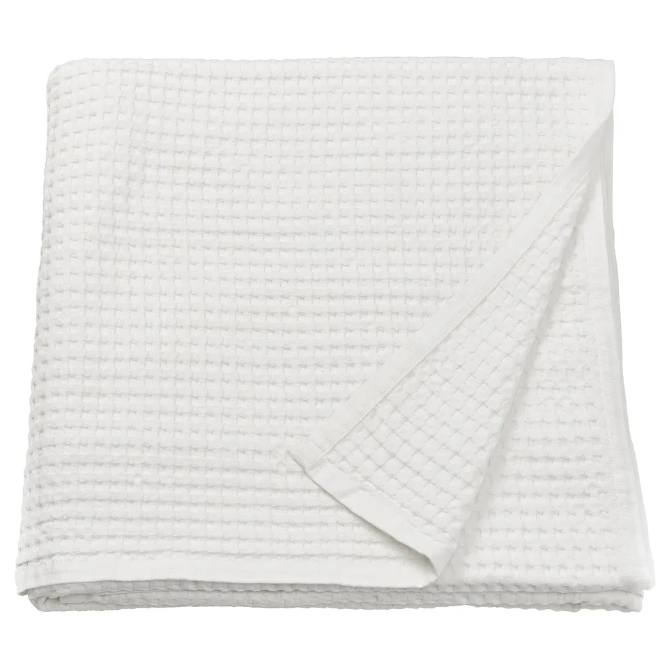 A PELARTUJA white bedspread, reversible, made of 100% cotton with a waffle weave texture, neatly folded.